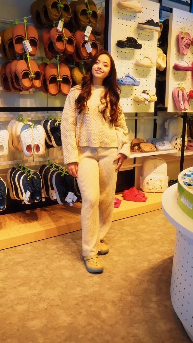 Cliente na loja entre as paredes de produtos Crocs